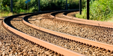 Togskinner i et sving med træer ved siden af