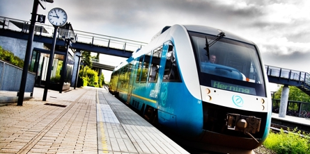 Et Arriva-tog i retning mod Herning holder ved en station
