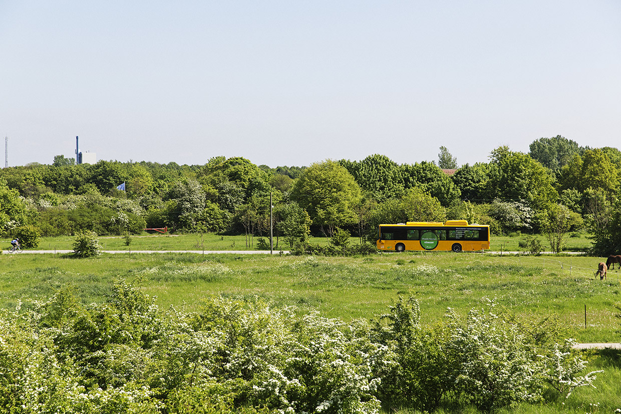 En elbus kører på en vej i grønne omgivelser