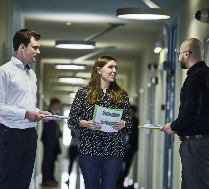 Tre af ministeriets medarbejder taler sammen på gangen i departementet.